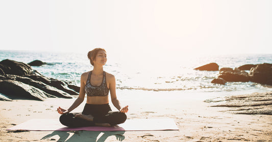 a woman is doing yoga on the beach