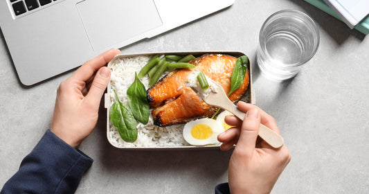 meat, egg, and vegetable in a lunch box beside laptop