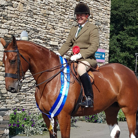 Man sat on horse with a winning rosette and sash