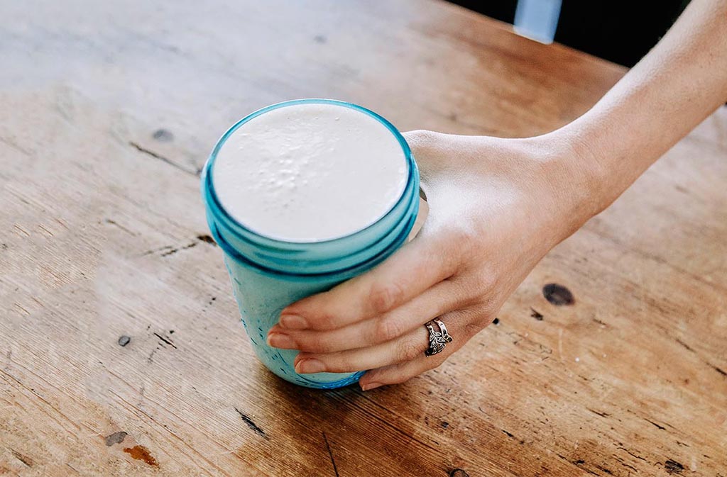 woman's hand holding a blue ball jar full of low carb protein shake