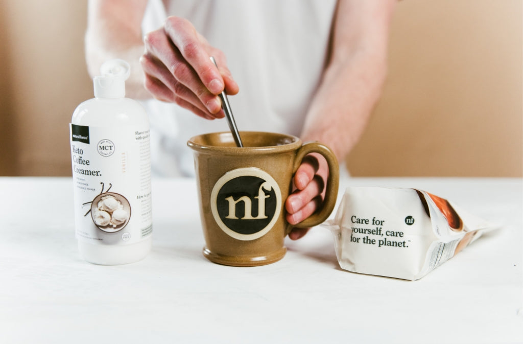 hand stirring one of the best keto recipes in a natural force mug flanked by natural force keto coffee creamer and collagen peptides