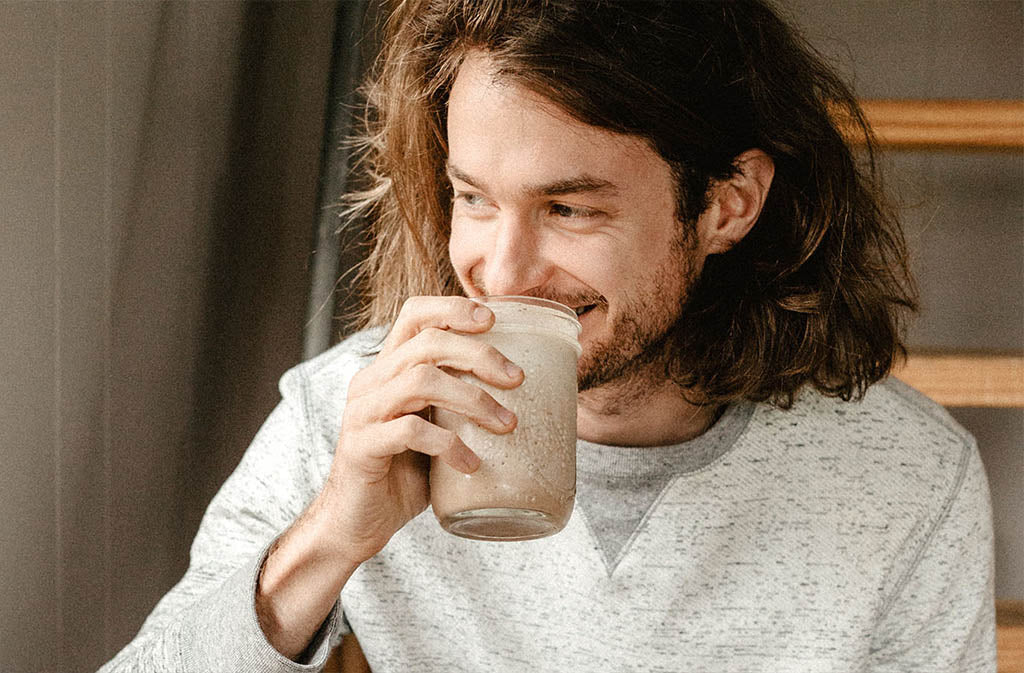 man smiling drinking a chocolate avocado smoothie