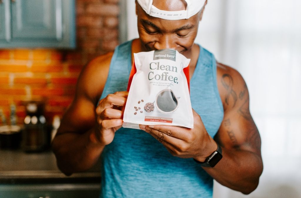 athletic man smiling as he smells an open bag of natural force clean coffee