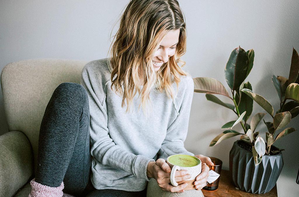 woman smiling at a mug of matcha