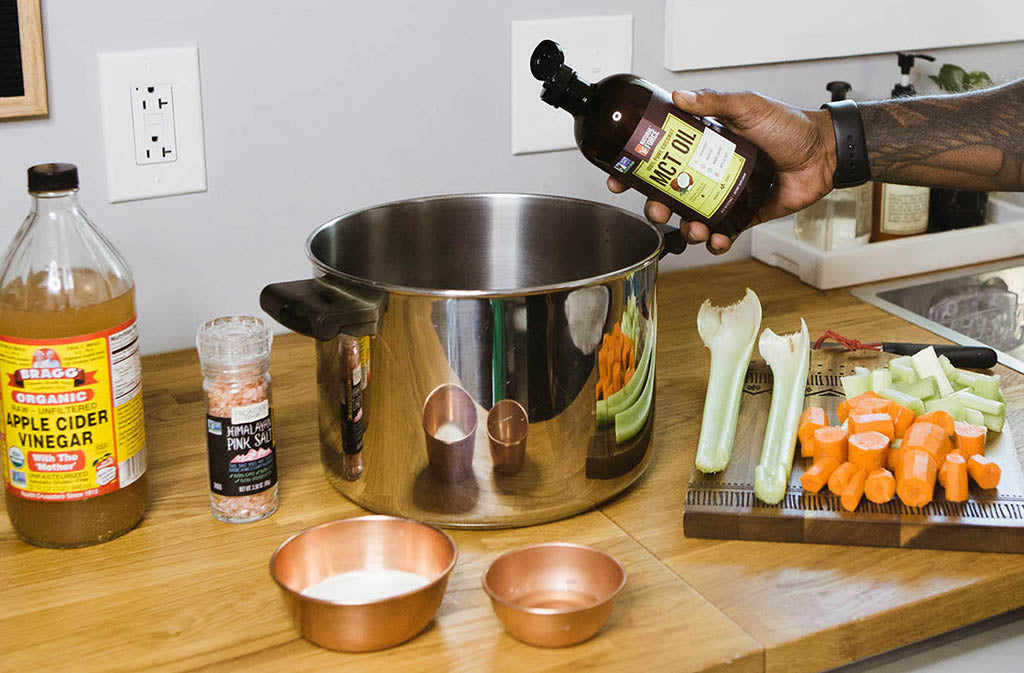 hand pouring natural force mct oil into a stock pot