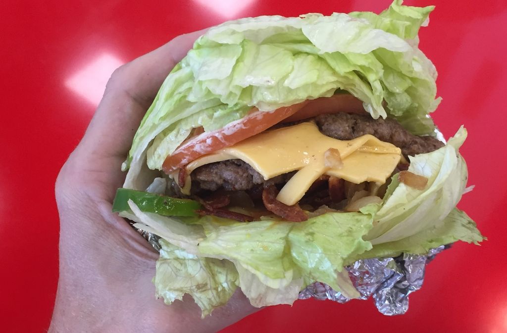 hand holding a keto five guys burger with a lettuce wrap