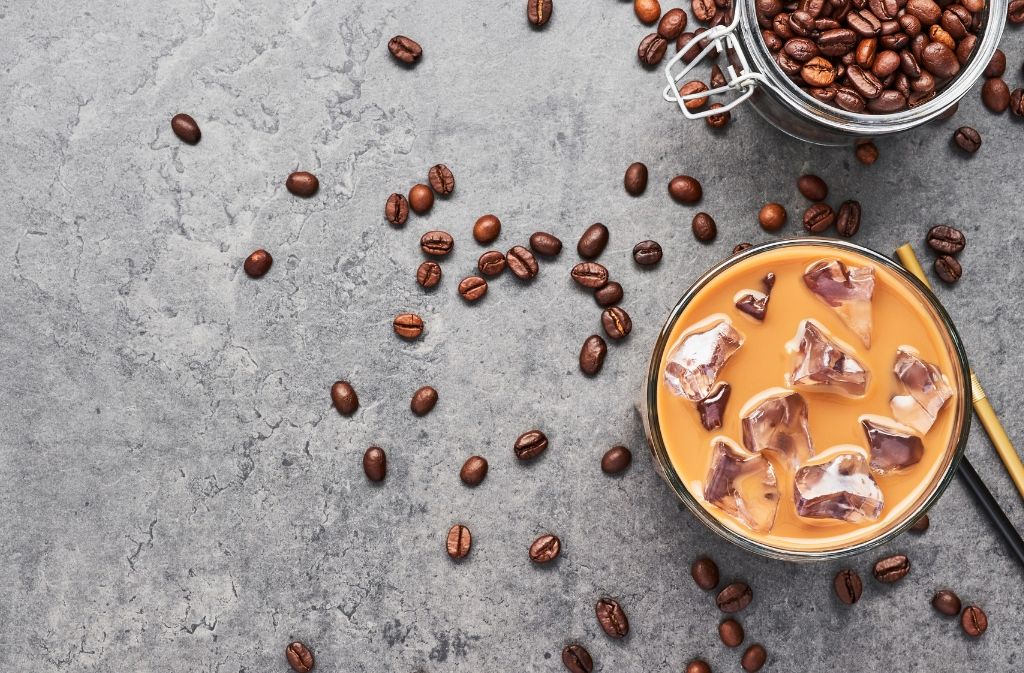 low carb salted caramel cold brew keto iced coffee in a cup surrounded by coffee beans