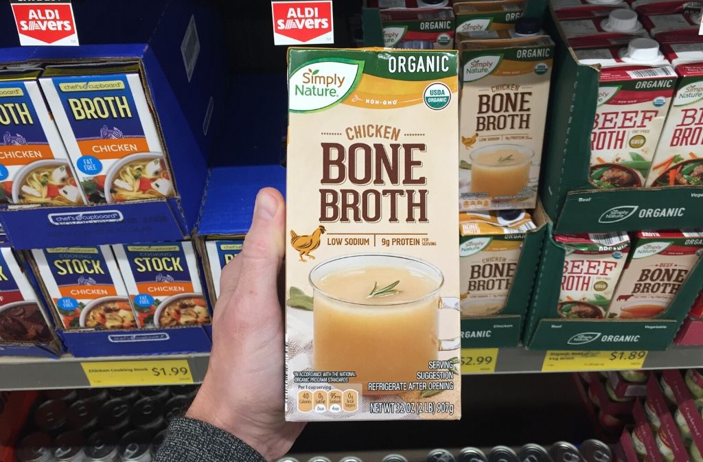 hand holding a container of bone broth
