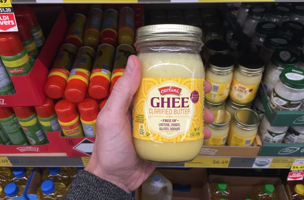 hand holding a jar of ghee