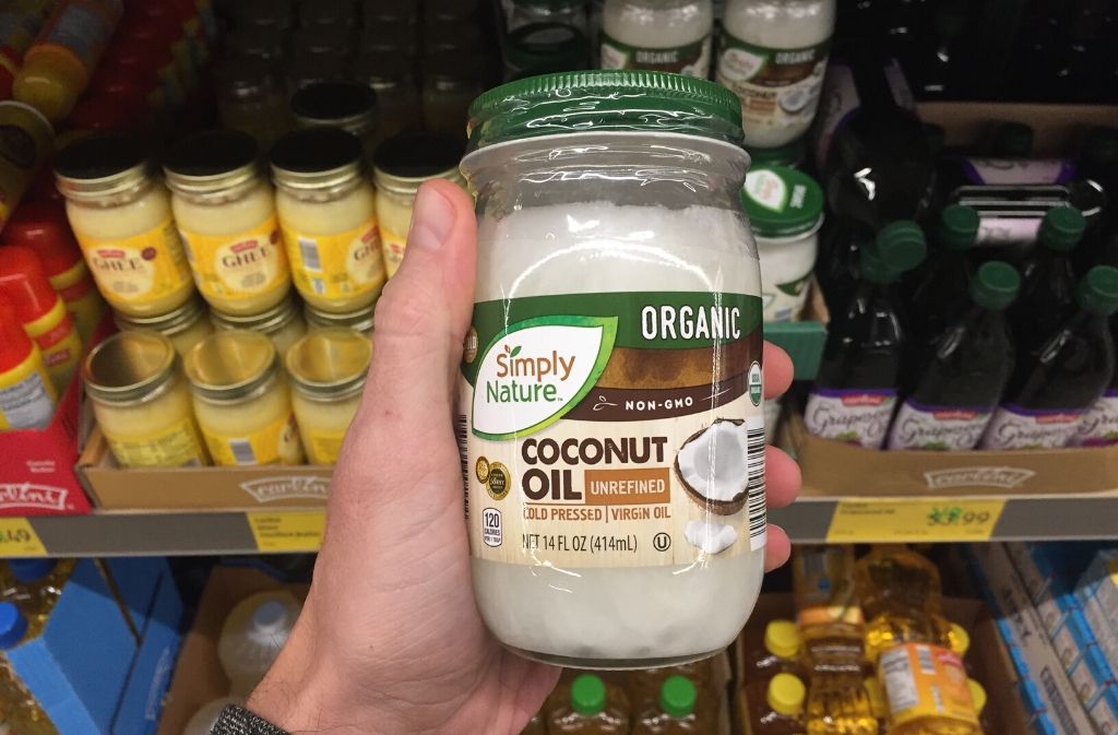 hand holding a jar of coconut oil