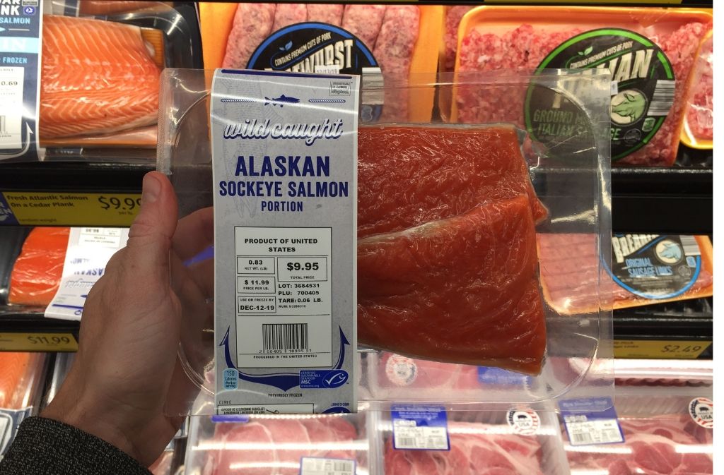 hand holding a package of wild caught salmon