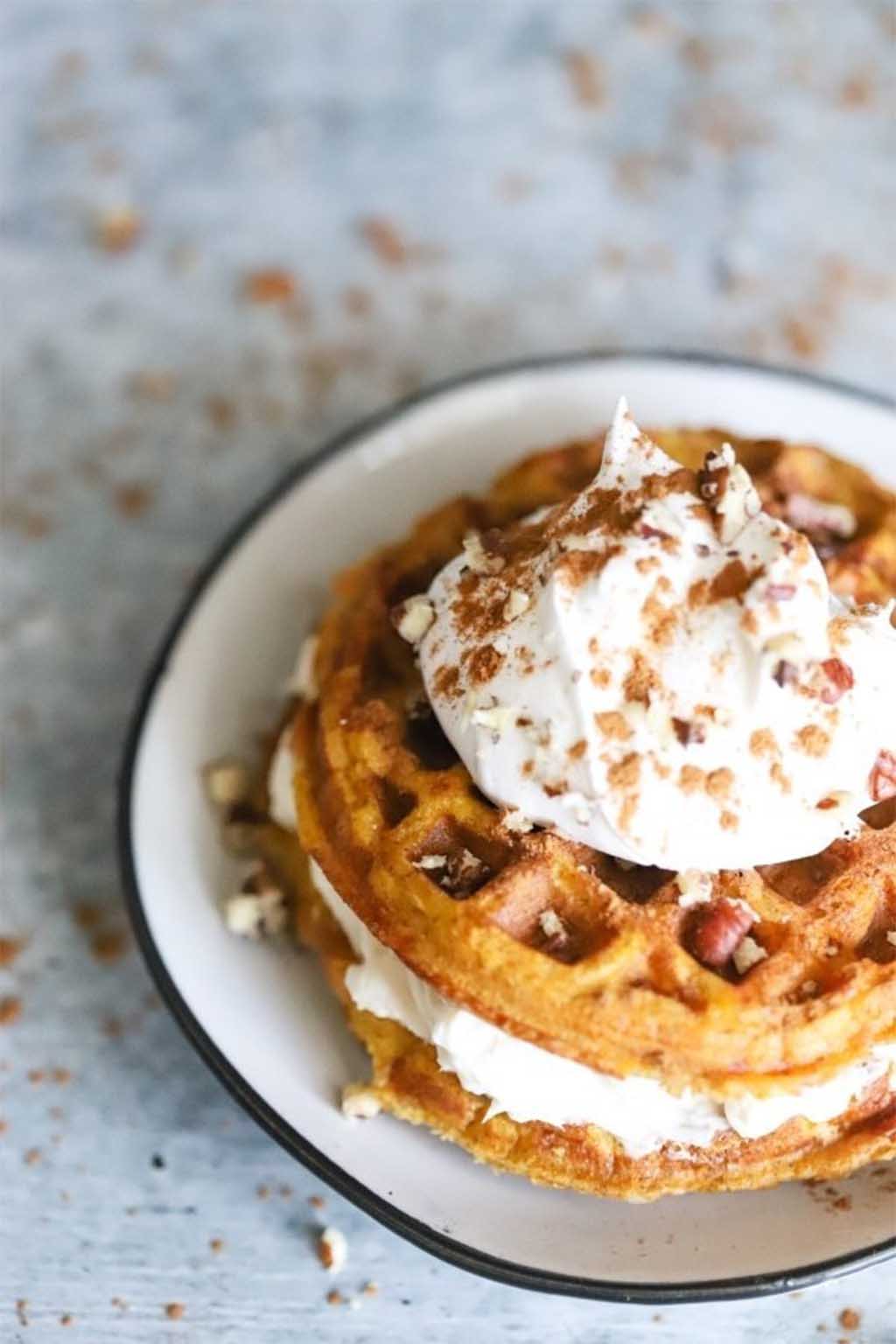 keto pumpkin chaffle cheesecake with whipped cream on a grey surface