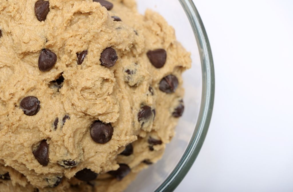 close up of a bowl of keto chocolate cookie dough on a white surface