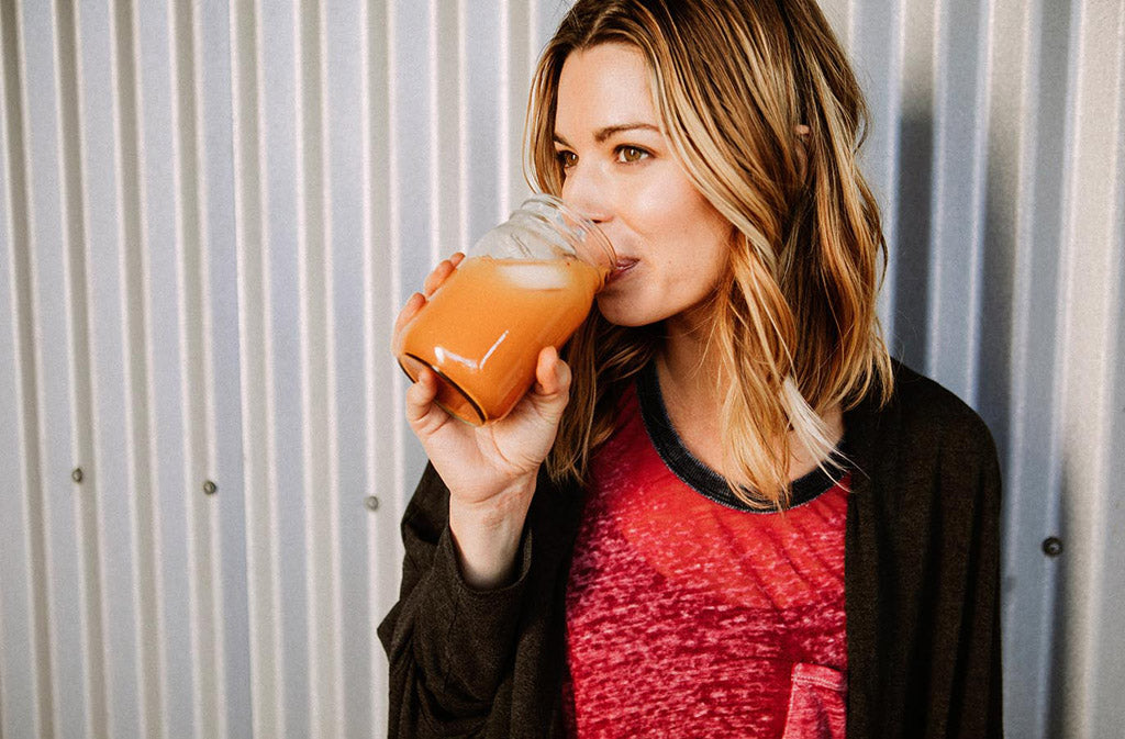 woman sipping a keto detox drink from a mason jar