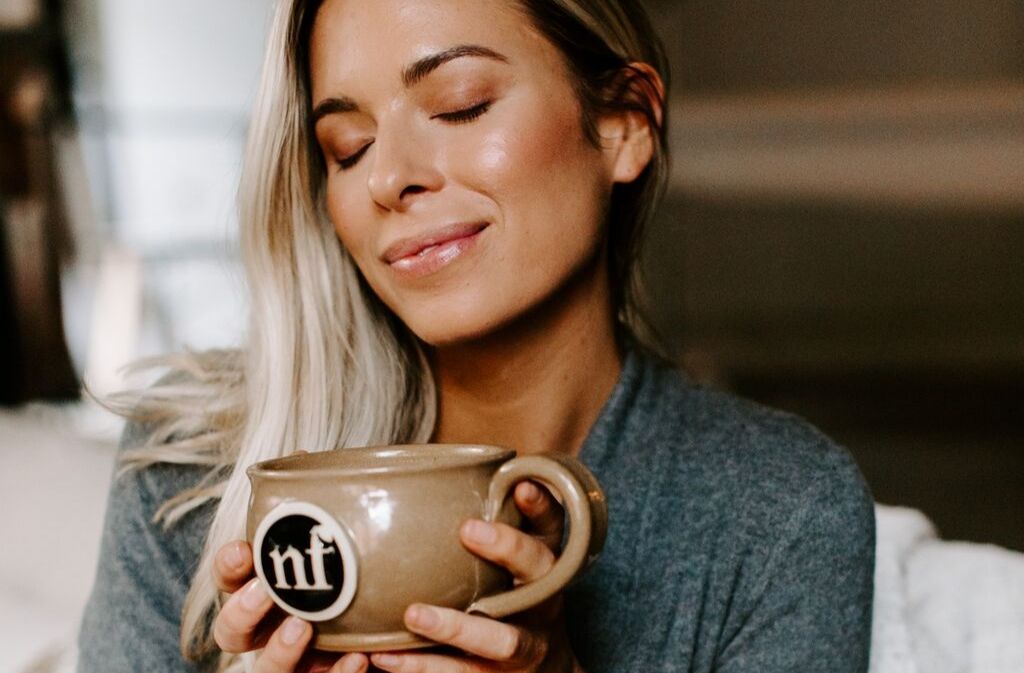 woman smiling while holding a handcrafted natural force mug