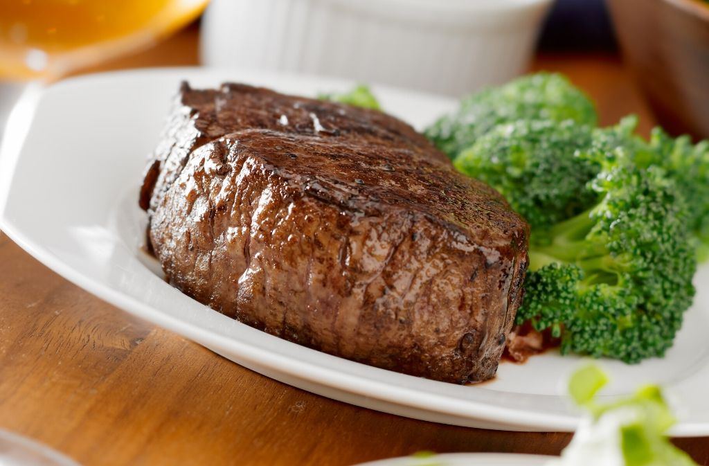 a white plate with a sirloin steak and broccoli