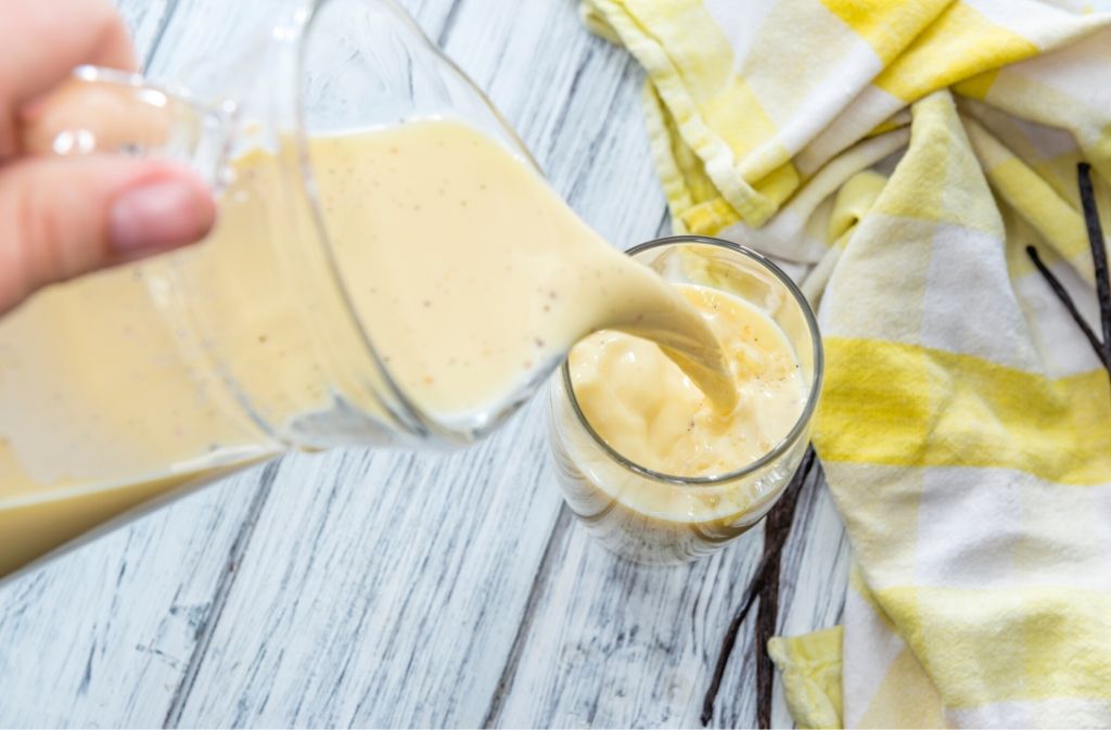 hand pouring lemon cake keto shake from a blender into a glass