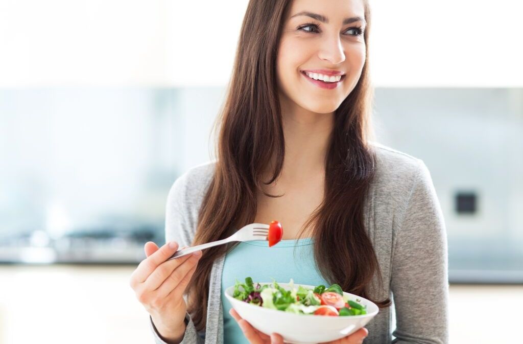woman looking relaxed while holding a salad and practicing mindful eating