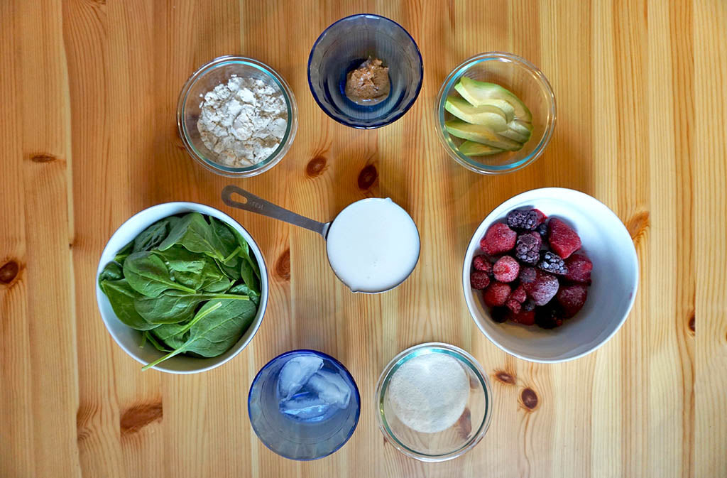 green protein smoothie ingredients displayed on a wood surface