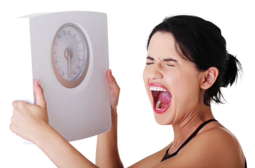 woman who is not losing weight on keto holding a scale and screaming