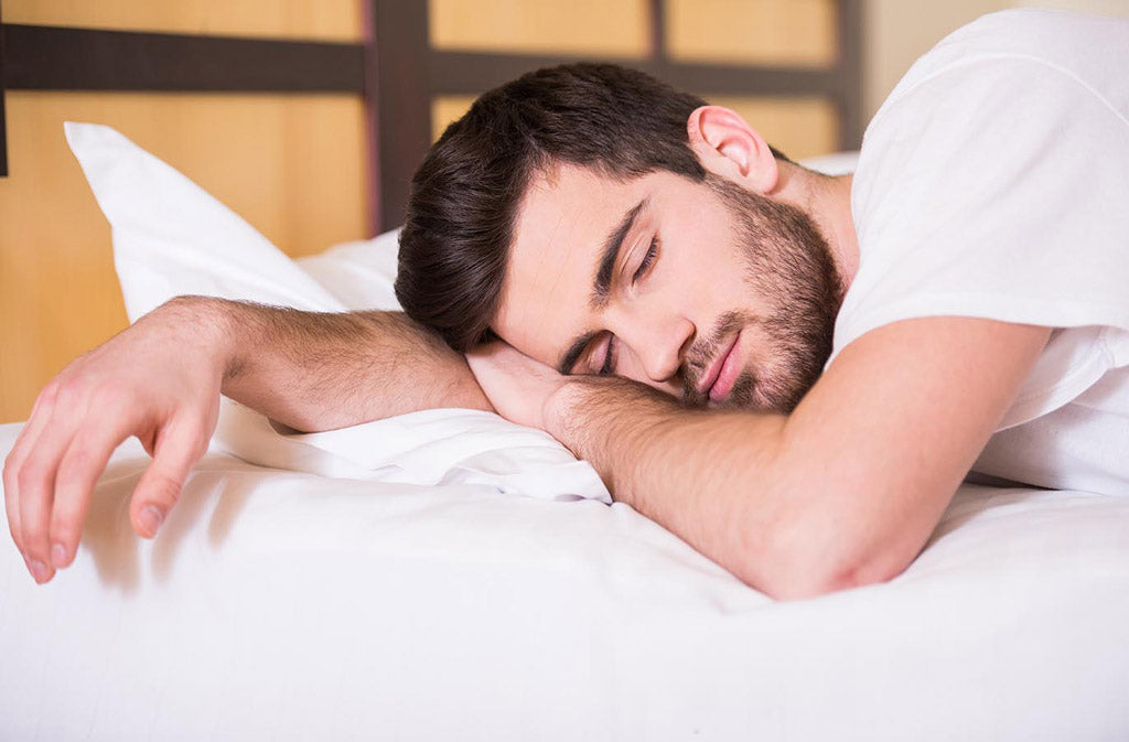 man sleeping on a white bed