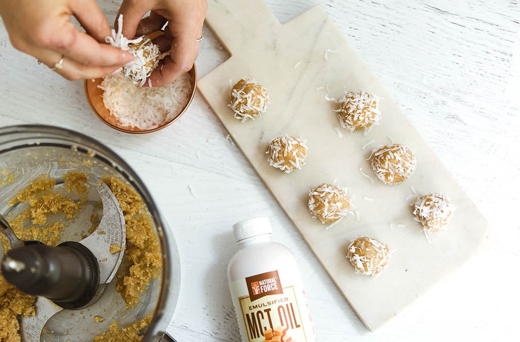 hand forming a low carb energy balls beside a tray with seven other low carb energy balls