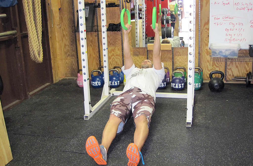 man in starting position for ring rows