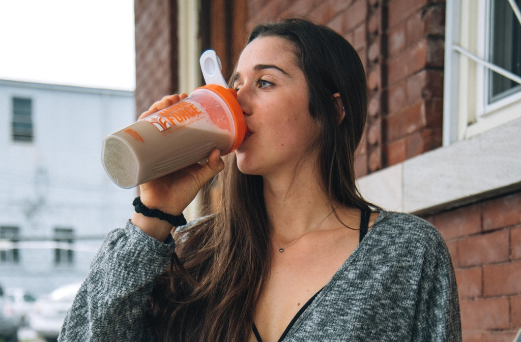 athletic woman drinking from a Natural Force blender bottle