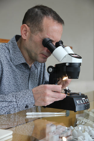 Bruce Eicher examines a piece of jewelry.