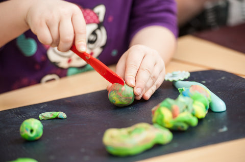 toddler playing with play doh cutting knife