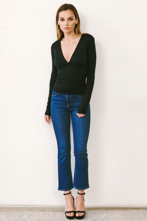 Full body image of chic casual outfit with soft black long sleeve top with blue jeans and heels