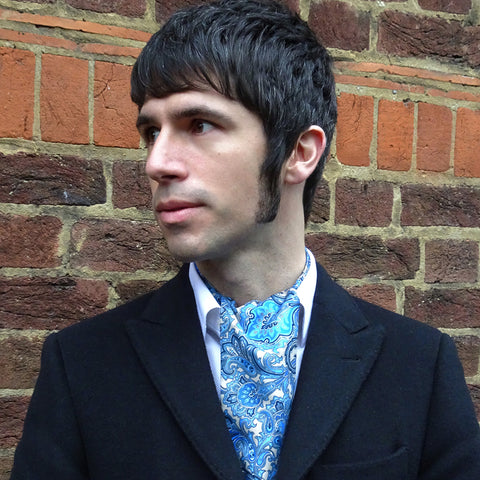Man wearing blue paisley scarf with dark blazer