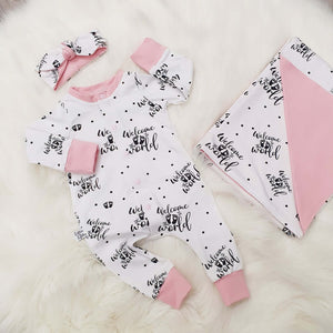 New baby gift set comprising a romper, blanket and headband made with bayridgecaskandkeg's Welcome to the world fabric which is white with black writing. The gift is accented with baby pink