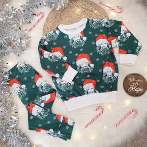 Children's christmas leggings. Green background featuring a special edition print of bayridgecaskandkeg's signature Lion print wearing a red and white santa style hat. White snowflakes adorn the background. The leggings are photographed against a white fluffy background with silver tinsel, red and white candy canes and fairy lights.