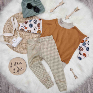 Kids outfit flat lay image featuring bayridgecaskandkeg sage grid leggings, retro smiley oversized sweatshirt and green knitted beanie hat