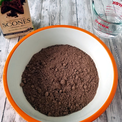 Dark Chocolate Scone Mix in a bowl with 2/3 cup of water next to it