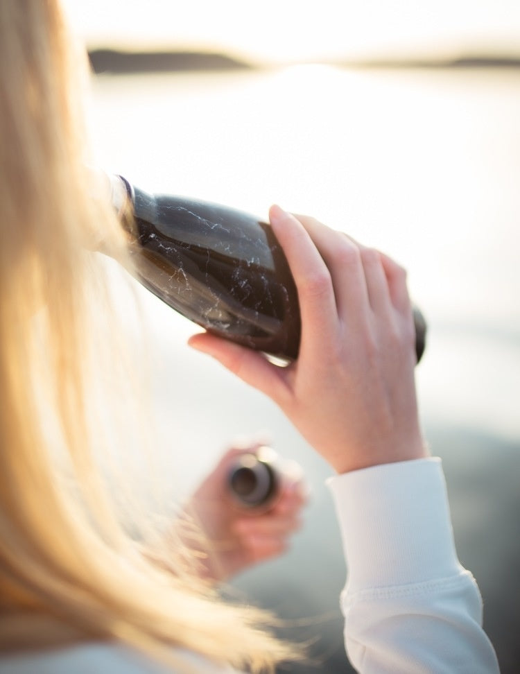 Kvinde drikker vand fra en genanvendelig drikkedunk fra danske Miin Bottle