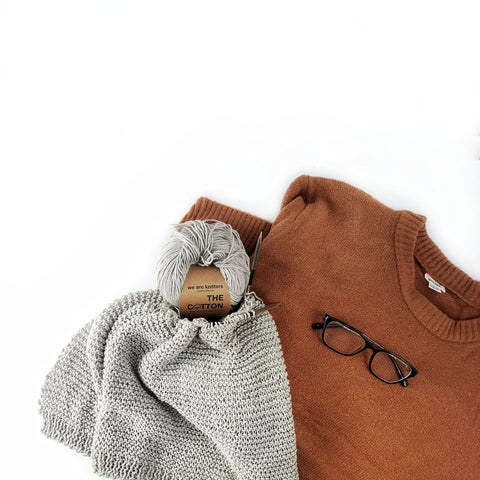 Garter stitch knitwear beside orange sweater and glasses