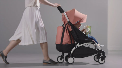 Woman pushing Babyzen Yoyo2 with rolling bag accessory attached