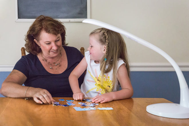 Stella lighting helping a grandmother make a puzele with her granddaughter