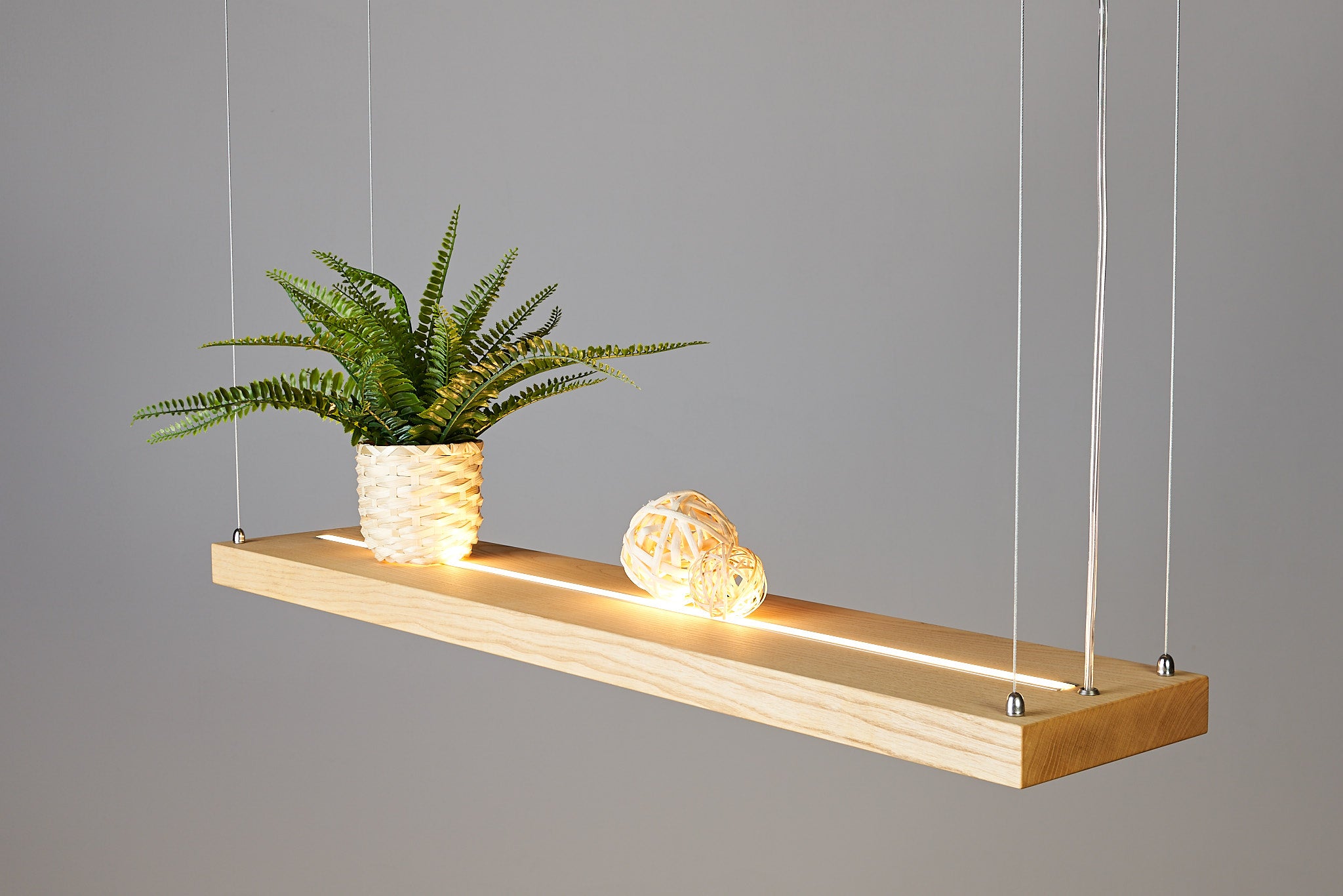 3-flammige LED Hängelampe aus Massivholz, Farbe Esche, Detailansicht der Maserung, Schräge Seitenansicht von oben der Hängelampe, so das man den einen LED Streifen oberhalb der Lampe sieht.