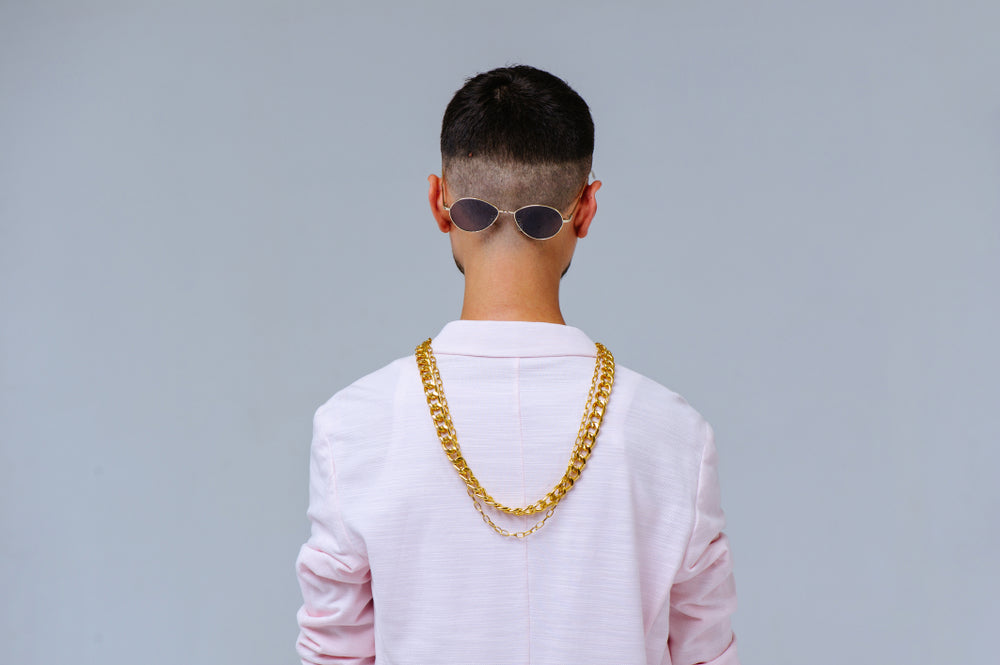 man in gold chains and sunglasses worn backwards