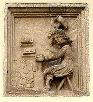 A Stone carving of a man hammering a coin at a work bench.