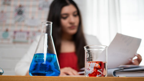 Melissa Maribel at desk with beaker and erlenmeyer flask