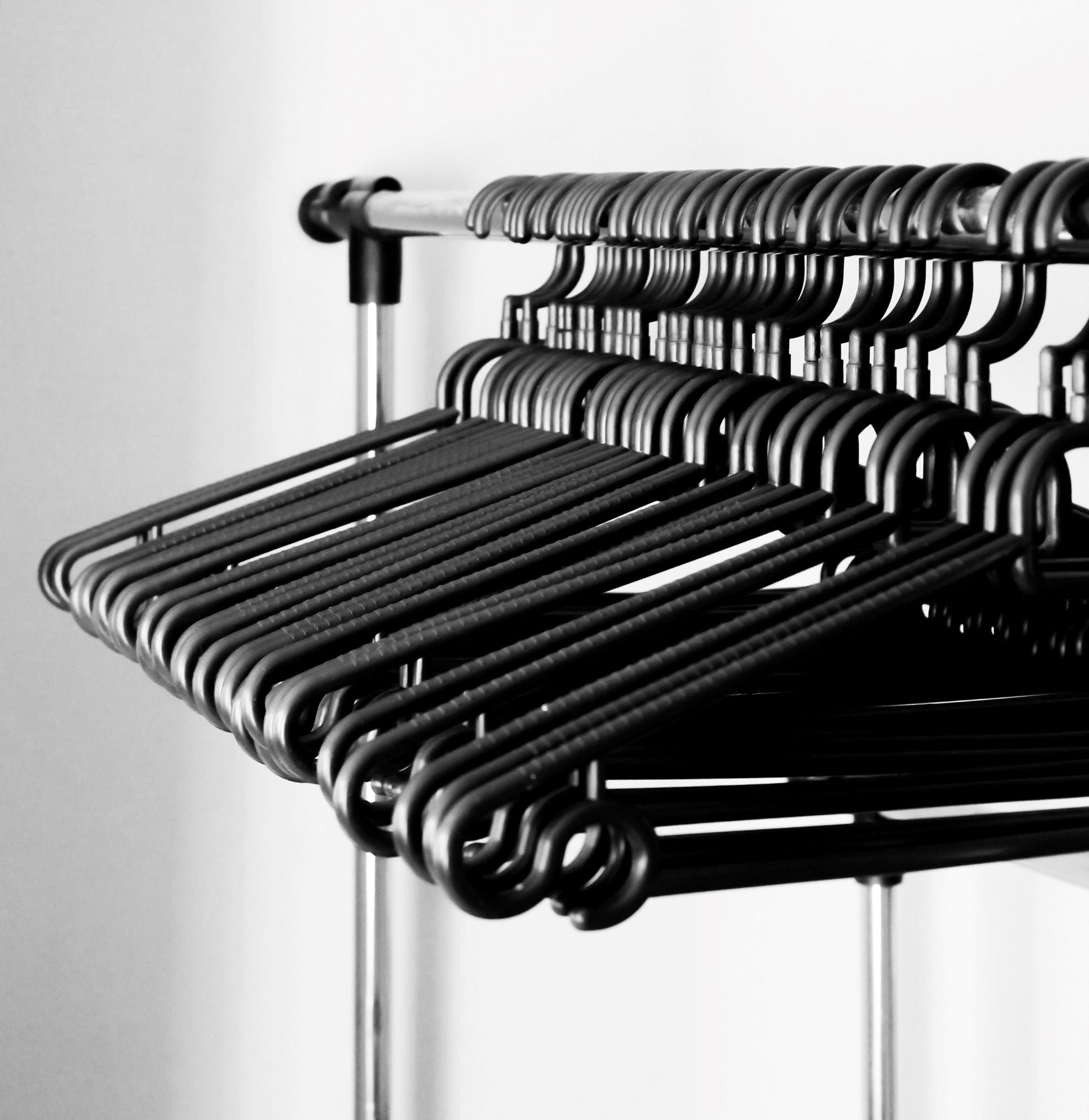 Black hangers made of moulded plastic stored on the closet rod
