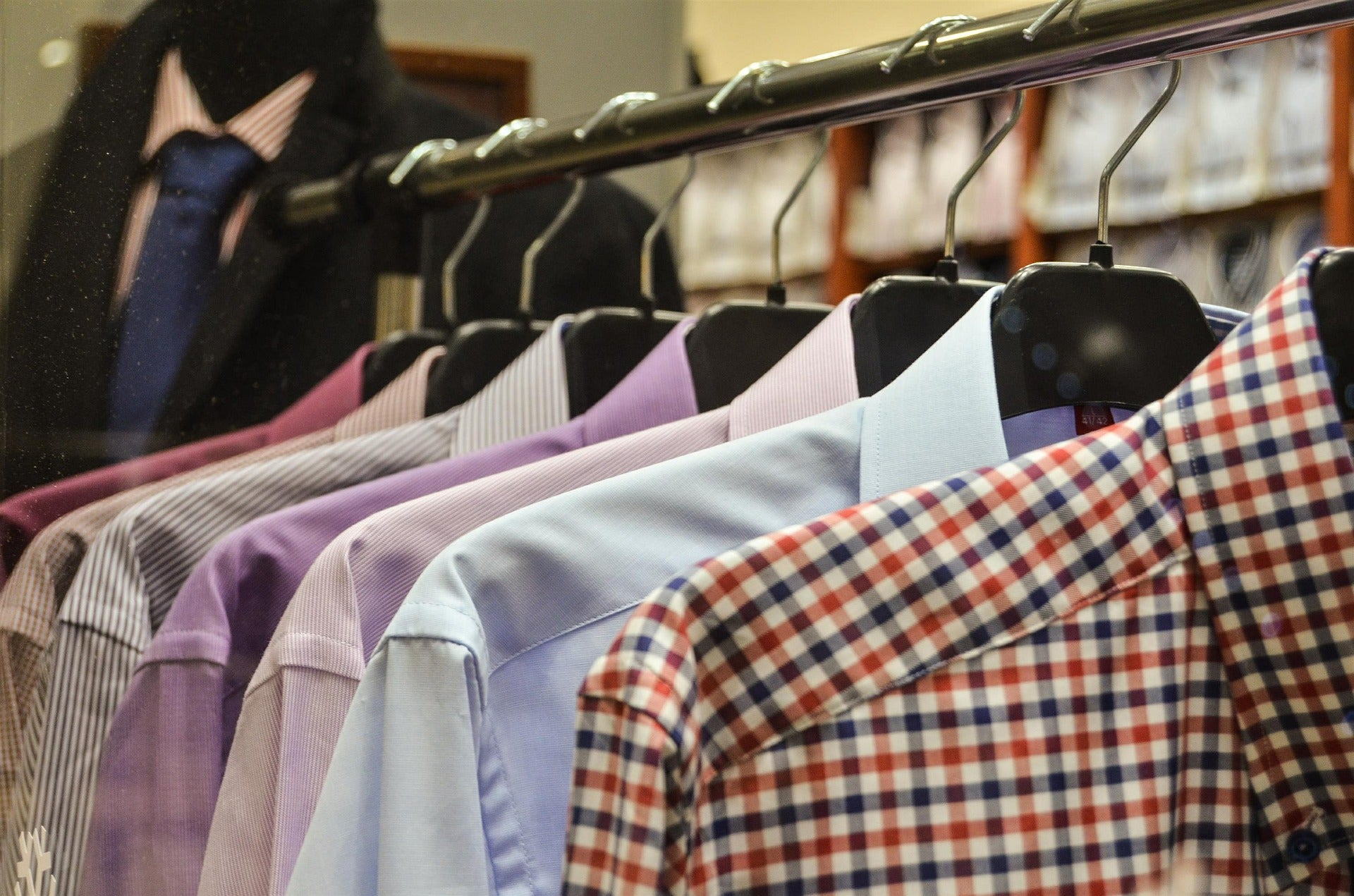 Colorful men’s shirts hung on plastic hangers and placed on a rack in a fashion-store