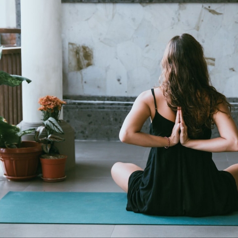 Yogi on a yoga mat, practicing a seated reverse prayer.