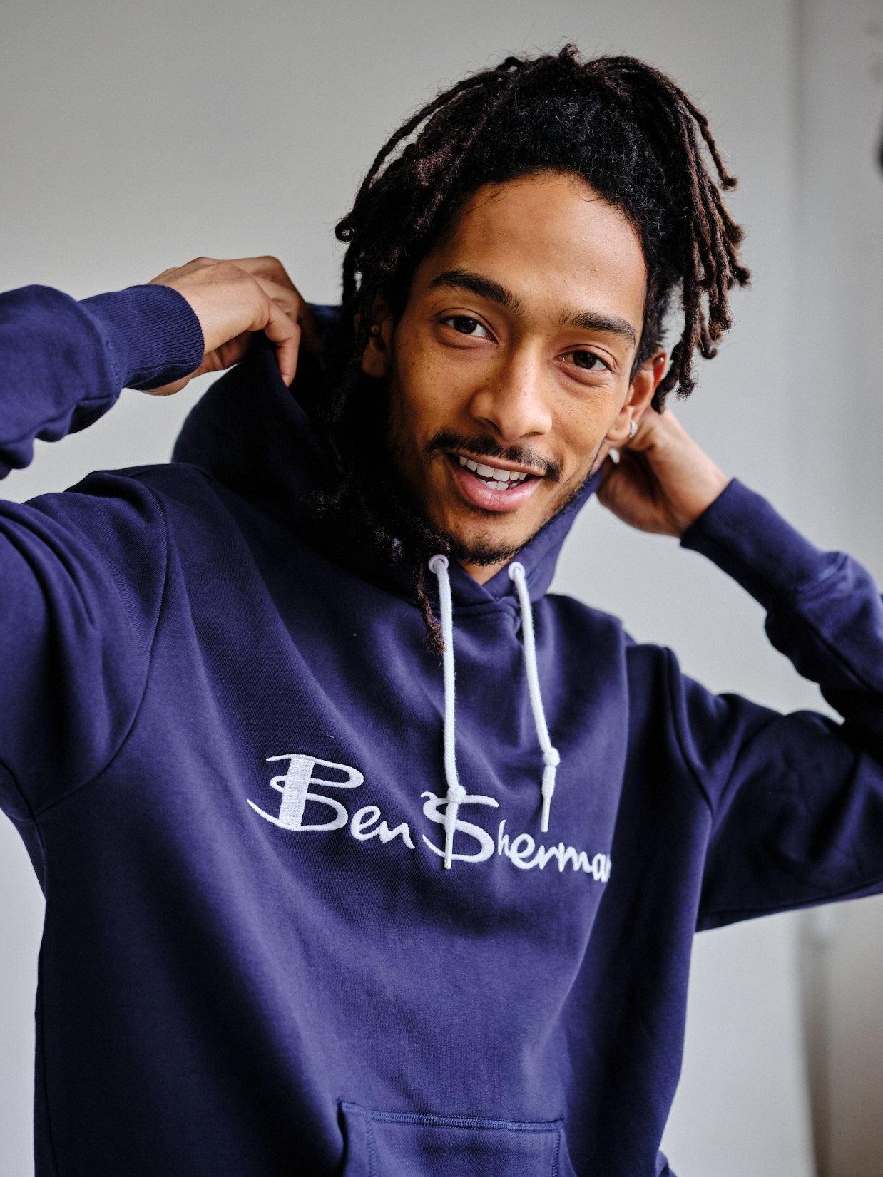 Thomas wears the Embroidered Logo Hoodie in dark navy