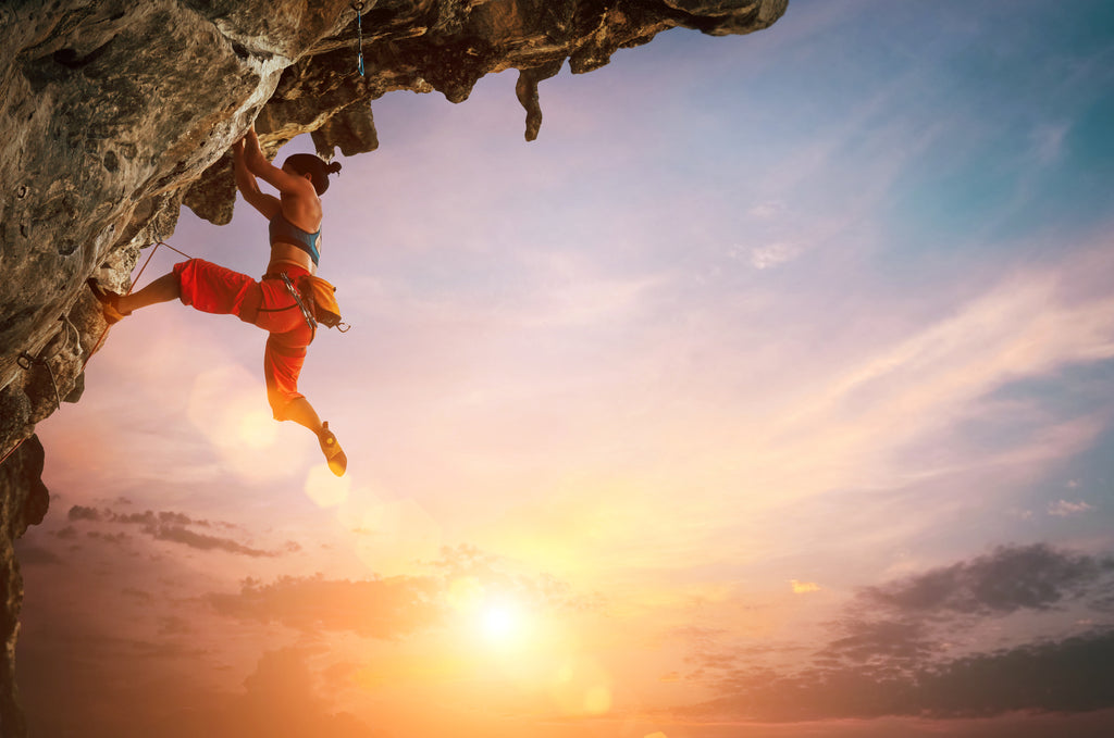 woman rock climbing outdoors at sunset