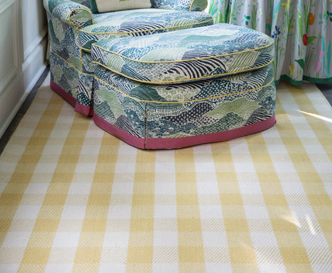 yellow and white tartan rug at the foot of a colorful arm chair